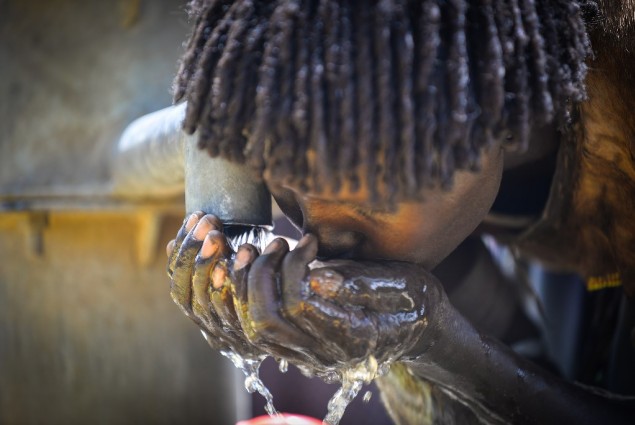 Image of woman drinking water from pump in Ethiopia