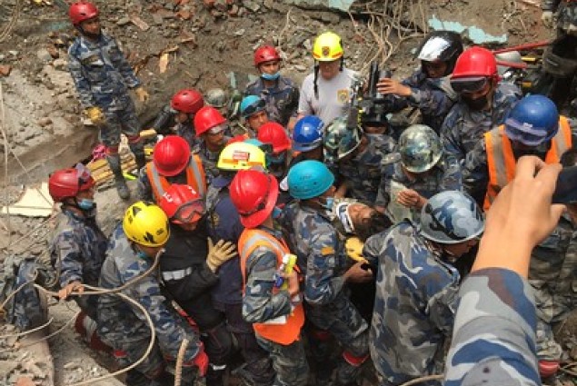 Members of a USAID DART help pull 15-year-old Pemba Tamang from rubble five days after a M7.8 earthquake in Nepal.
