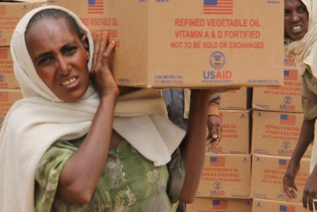 A resident of the Hawzien Woreda carries a box of cooking oil from the food distribution site. The oil will be distributed to food insecure families in her community. USAID purchased the oil for residents in the region in support of the Government of Ethiopia's Productive Safety Net Program.
