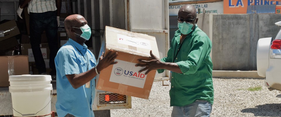 Men unload a box labeled with the USAID logo