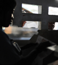 A poll worker reads out vote results on March 20, 2011, in Port-au-Prince as people peer through nearby windows. USAID assisted 