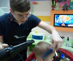 Tymofii Babych cuts a child’s hair at his business, which he started with USAID's TEAM project funding