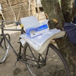 José Azevedo's bicycle is standing against a tree, with a local straw hut in the back suggesting one of Azevedo's health visits.