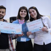 Two young women and a young man hold competition prize certificates for 1,000 euro