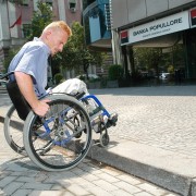 A young man in a wheelchair accessing a sidewalk without a wheelchair ramp
