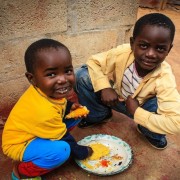 Two young boys eat outside their home