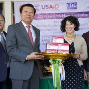Dr. Phouthone Muoangpak (center left), Vice Minister of Health, receives 100,000 rapid diagnostic test kits from U.S. Ambassador to Laos Rena Bitter (center right) at a handover ceremony in Vientiane on December 6.
