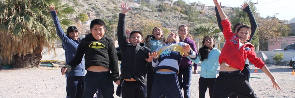 A group of smiling children jumping with hands in the air