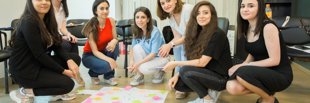 A group of women pose in front of a poster with sticky notes for a cooperative activity